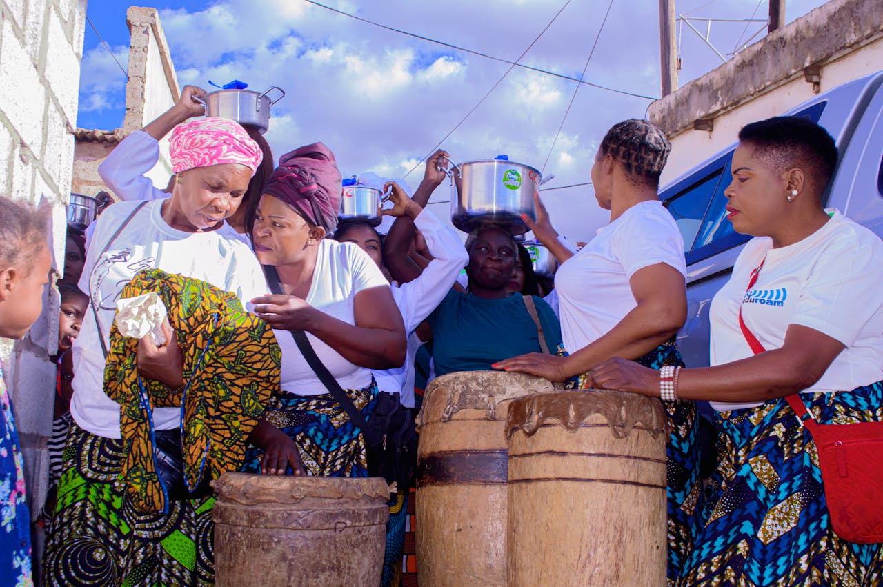 A lively group of women celebrating with music and traditional drumming outdoors.