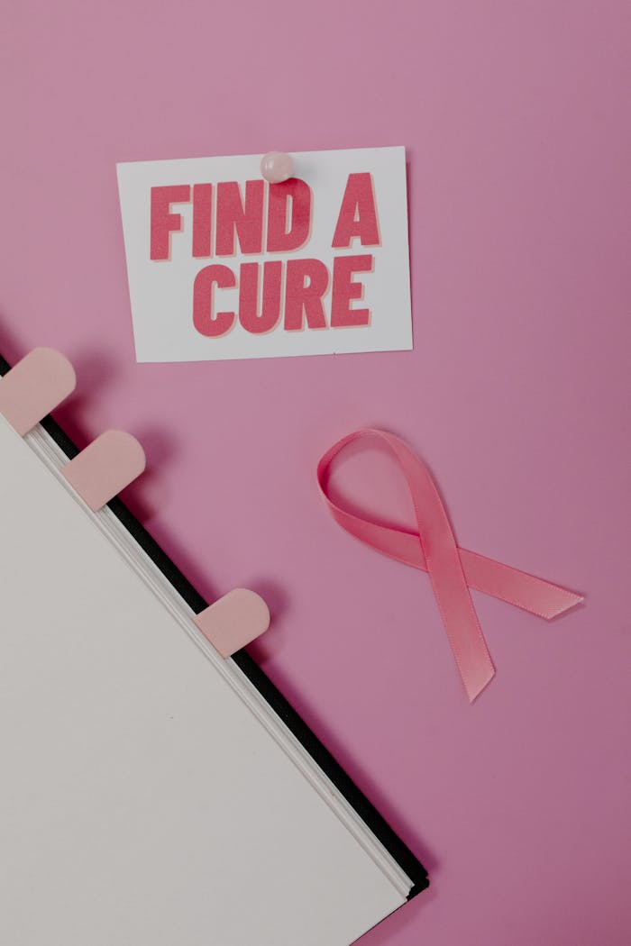Pink ribbon and 'Find a Cure' card symbolizing cancer awareness on a pink background.